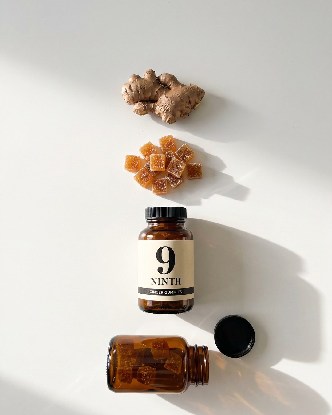 A top-down row on white: raw ginger, a pile of gummies, a full NINTH bottle and an open bottle on its side