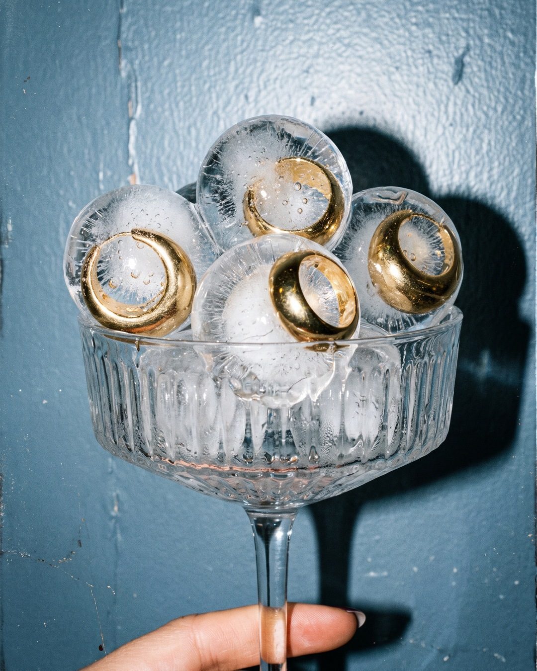 A crystal coupe heaped with ice spheres, each with a chunky gold ring frozen inside